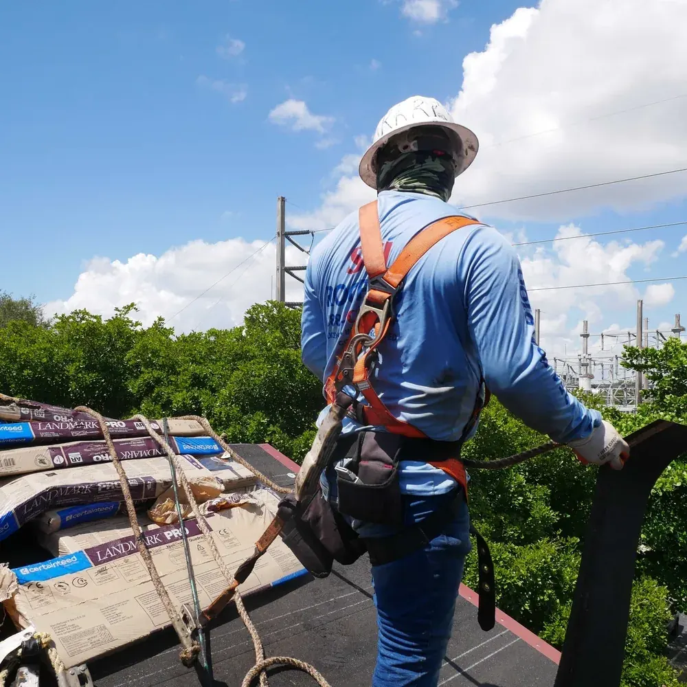 SCI Roofing crew member in a full safety harness working on a rooftop in South Florida